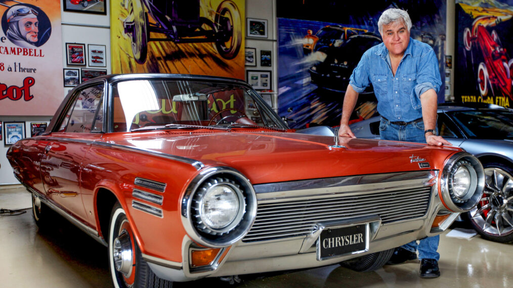 Talk show host and comedian Jay Leno stands next to a Chrystler Turbine at Jay's Garage in Burbank, CA