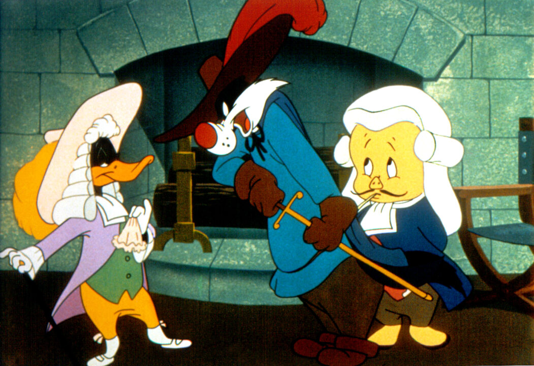 (l-r) Daffy Duck standing confidently in a powdered wig and 18th-century attire, Sylvester the Cat dressed as an 18th-century swordsman, about to draw his sword on Daffy, and Porky Pig with powdered wig, mustache and wearing 18th-century attire in the 1950 Looney Tunes animated short <i>The Scarlet Pumpernickel</i>