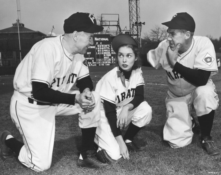 Paul Douglas and Janet Leigh in a scene from the 1951 baseball fantasy film Angels in the Outfield. They are both crouched down on a baseball field, wearing Pirates uniforms.