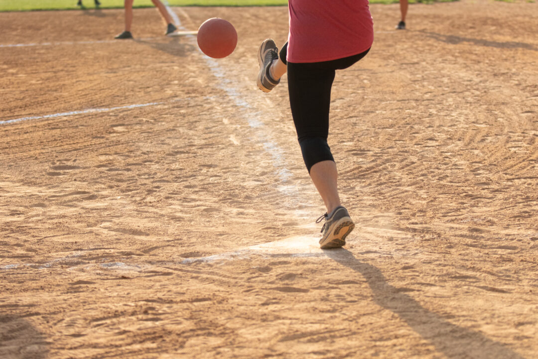 Adult Woman playing kickball in a public park league