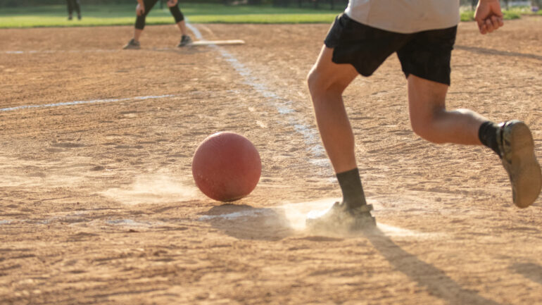 Adult Man playing kickball in a public park league