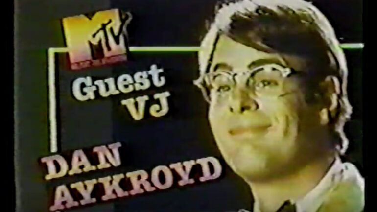 title screen from late May 1983, when Dan Aykroyd was a guest VJ on MTV for an hour. Aykroyd's headshot is on the right side and he is wearing glasses and a bowtie, in character from his movie 