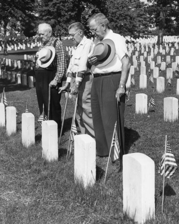 Veterans, from left to right, John Tabor, Edgar Fowdle, and Harry Meadows, pay tribute to fallan comrades buried in the Cemetary of the U.S. Soldiers. The graves are decorated in preparation for Memorial Day