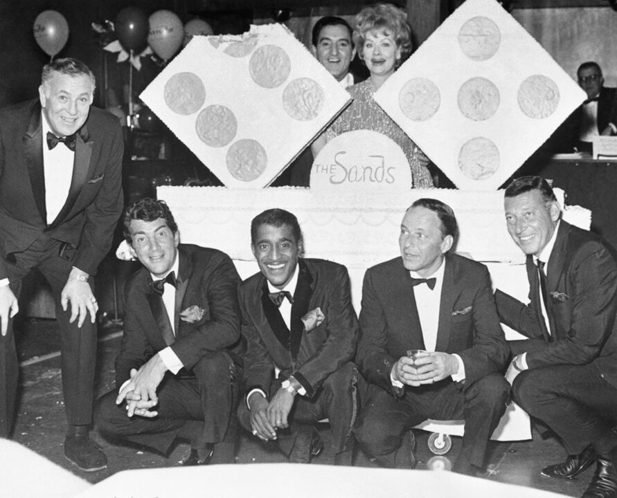 Dean Martin, Sammy Davis Jr., Danny Thomas, Lucille Ball, Frank Sinatra stand around a cake for the eleventh anniversary of the Sands Hotel in Las Vegas. On the extreme left is Sands President Jack Entratter