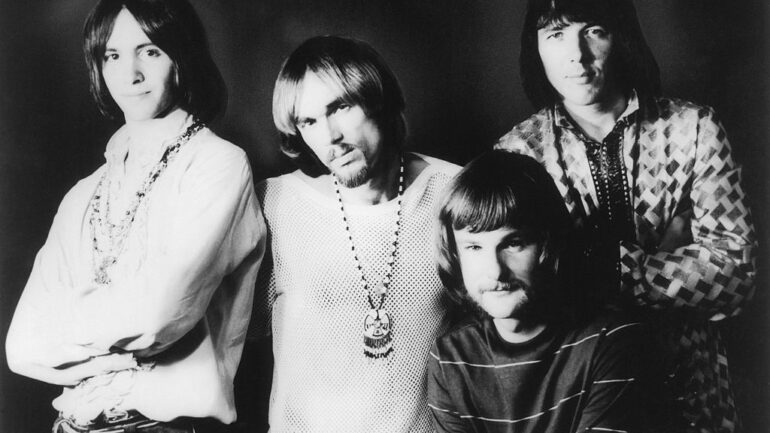 a black-and-white photo of the rock band Iron Butterfly from 1969. Left to right are Erik Brann, Ron Bushy, Lee Dorman and Doug Ingle. They are all white men with long hair fashionable at the time. Bushy has a mustache and goatee; Dorman a mustache; the other two are clean-shaven.