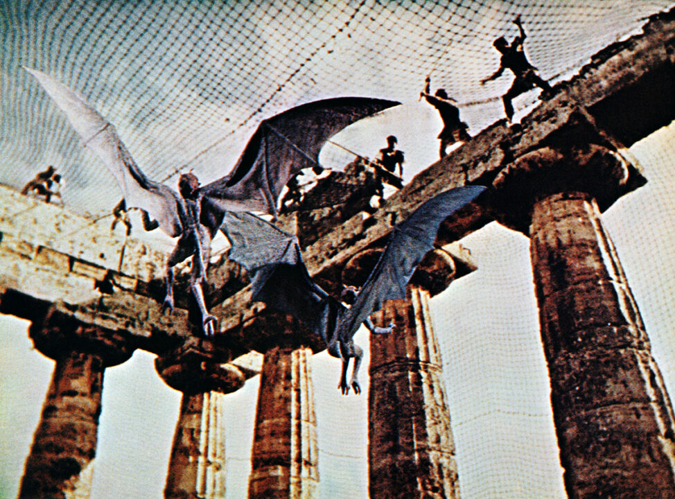 shot from the 1963 movie "Jason and the Argonauts," depicting Jason and his crew trapping two harpies -- flying creatures who look human-like, but also like demons, and with bat-like wings -- within the columns of an ancient ruin by placing a net across the top of the columns.