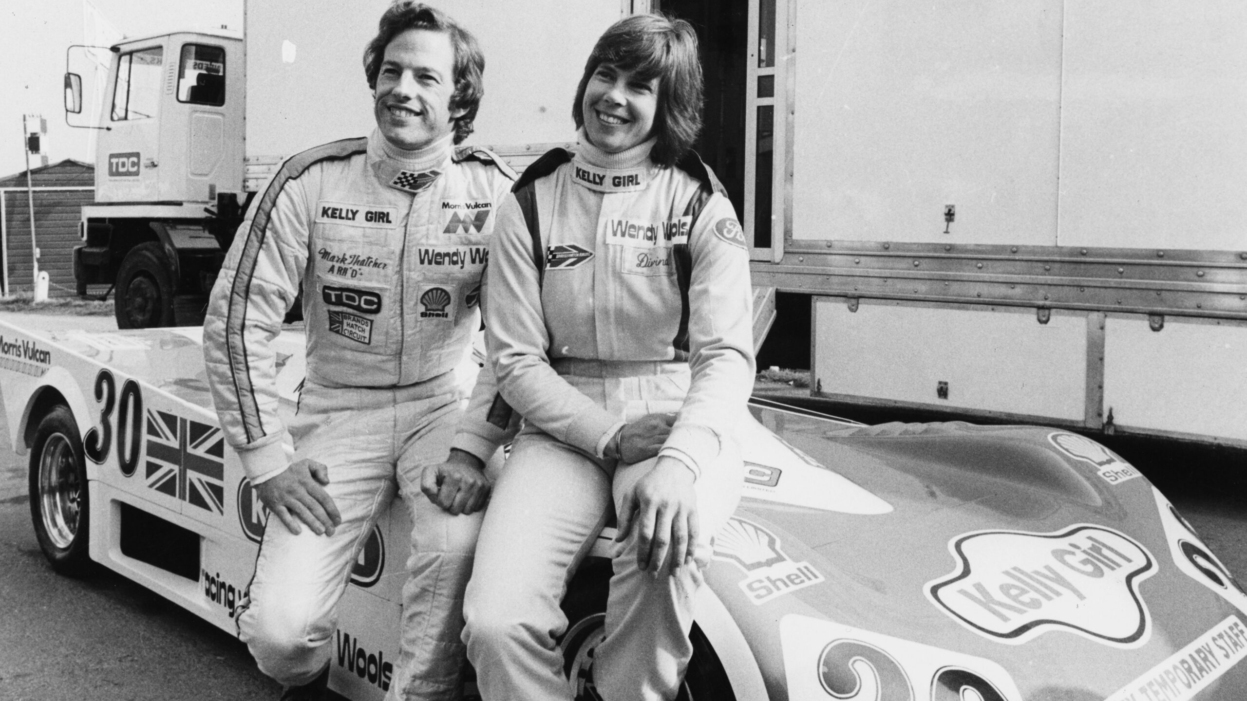 Racing drivers Davina Galica and Mark Thatcher, son of British Prime Minister Margaret Thatcher, sitting on the bonnet of a new car prior to competing in the World Championship race at Brands Hatch, England, February 29th 1980. 