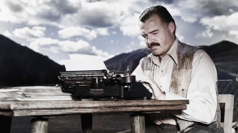 7th October 1939: EXCLUSIVE American writer Ernest Hemingway (1899 - 1961) works at his typewriter while sitting outdoors, Idaho. Hemingway disapproved of this photograph saying, 'I don't work like this.'