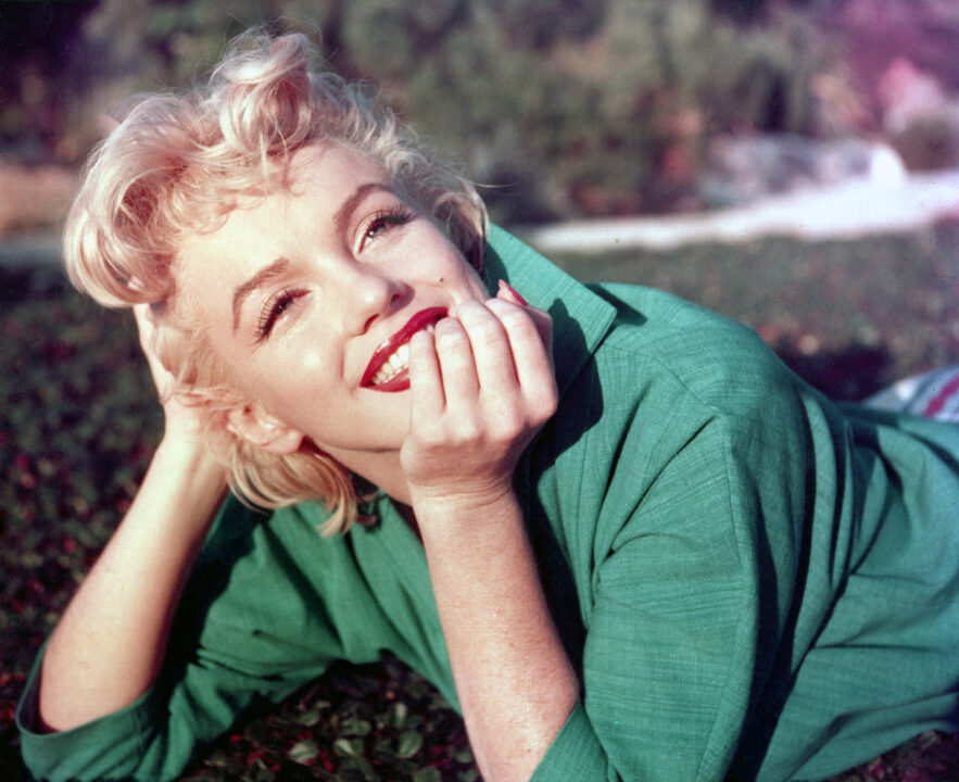 PALM SPRINGS, CA - 1954: Actress Marilyn Monroe poses for a portrait laying on the grass in 1954 in Palm Springs, California. 