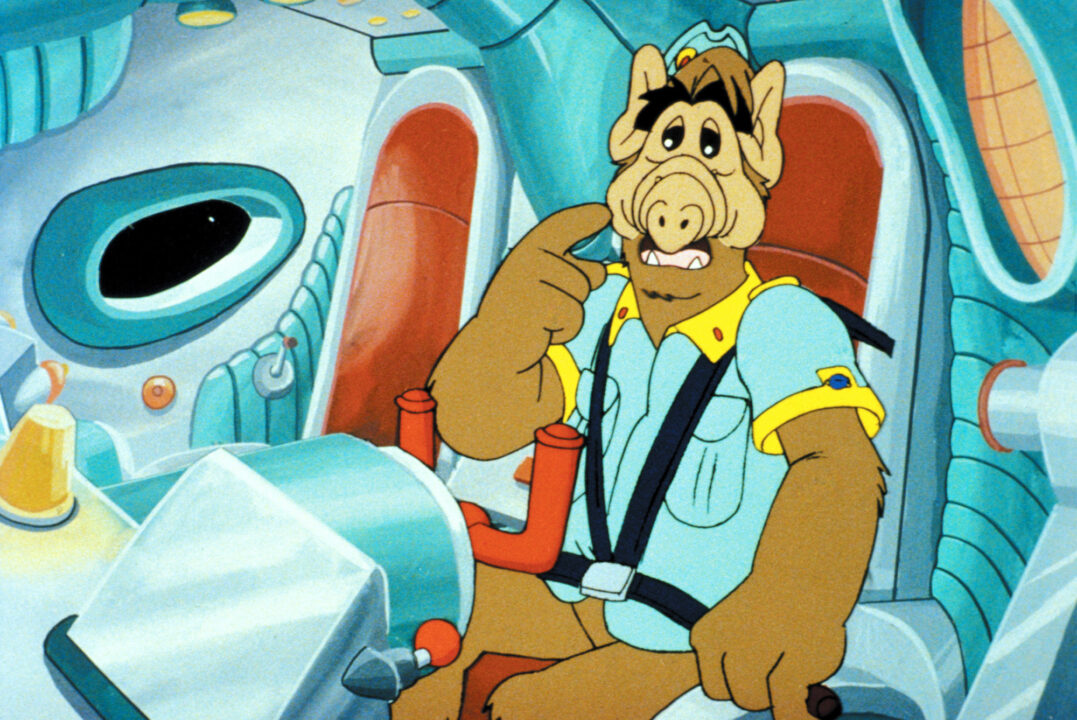 image from "ALF: The Animated Series." It is a cartoon drawing of ALF, a furry brown alien, who is sitting in his spaceship.