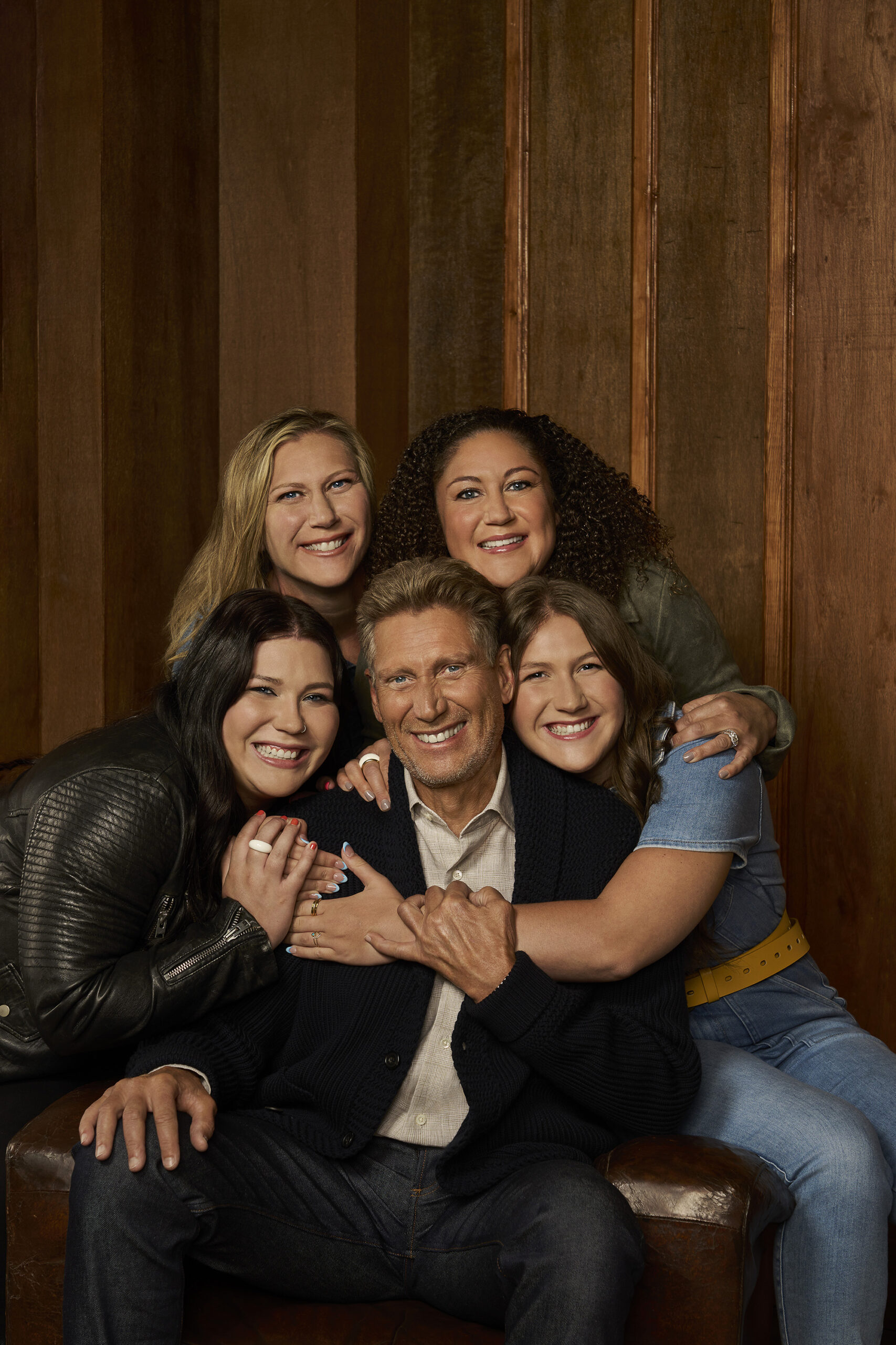 promotional photo for ABC's "The Golden Bachelor." Golden Bachelor Gerry Turner is seated, and surrounding him, and giving him hugs, are his two daughters and two granddaughters.