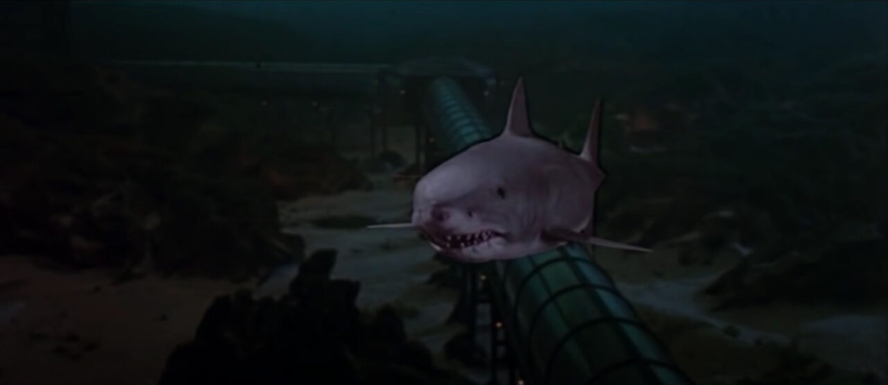 image from the 1983 movie "Jaws 3-D." it is a shot of a great white shark headed toward the camera underwater over the underwater passageways of a marine theme park. The shark is obviously superimposed and looks fake largely due to the 3-D effects used to produce the film for its original release.