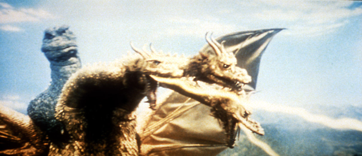 photo from the 1968 Toho movie "Destroy All Monsters." It is a scene from the climactic monster battle on Mt. Fuji, with a closeup of the three-headed dragon King Ghidorah shooting rays from one of its mouths. Behind him is Godzilla, coming in for an attack.