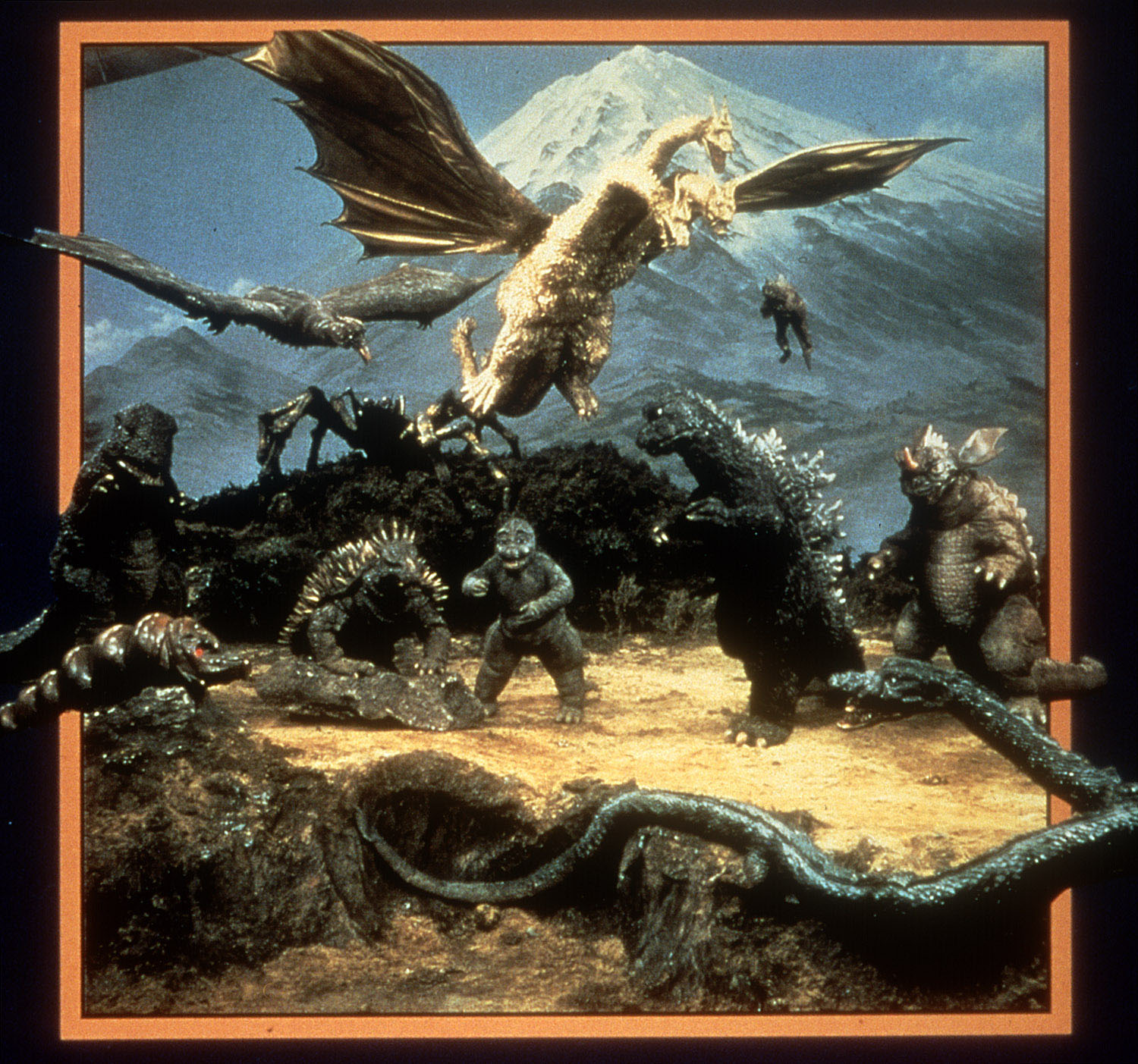 promo image for the 1968 movie "Destroy All Monsters." It depicts the 11 monsters featured in the movie, all in front of Mt. Fuji, where the final battle takes place. Featured, clockwise from top left: Rodan, Ghidorah, Varan (these three are flying), Godzilla, Baragon, Manda, Minilla, Anguirus, Mothra, Gorosaurus and Kumonga.