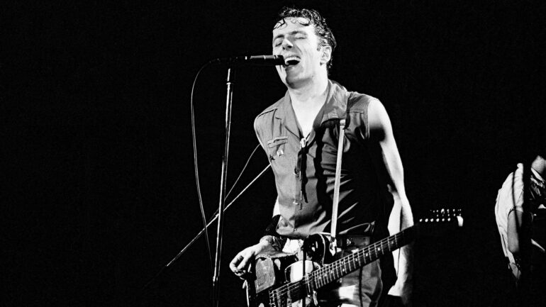 black and white 1981 photo of Joe Strummer, performing as lead vocalist for The Clash