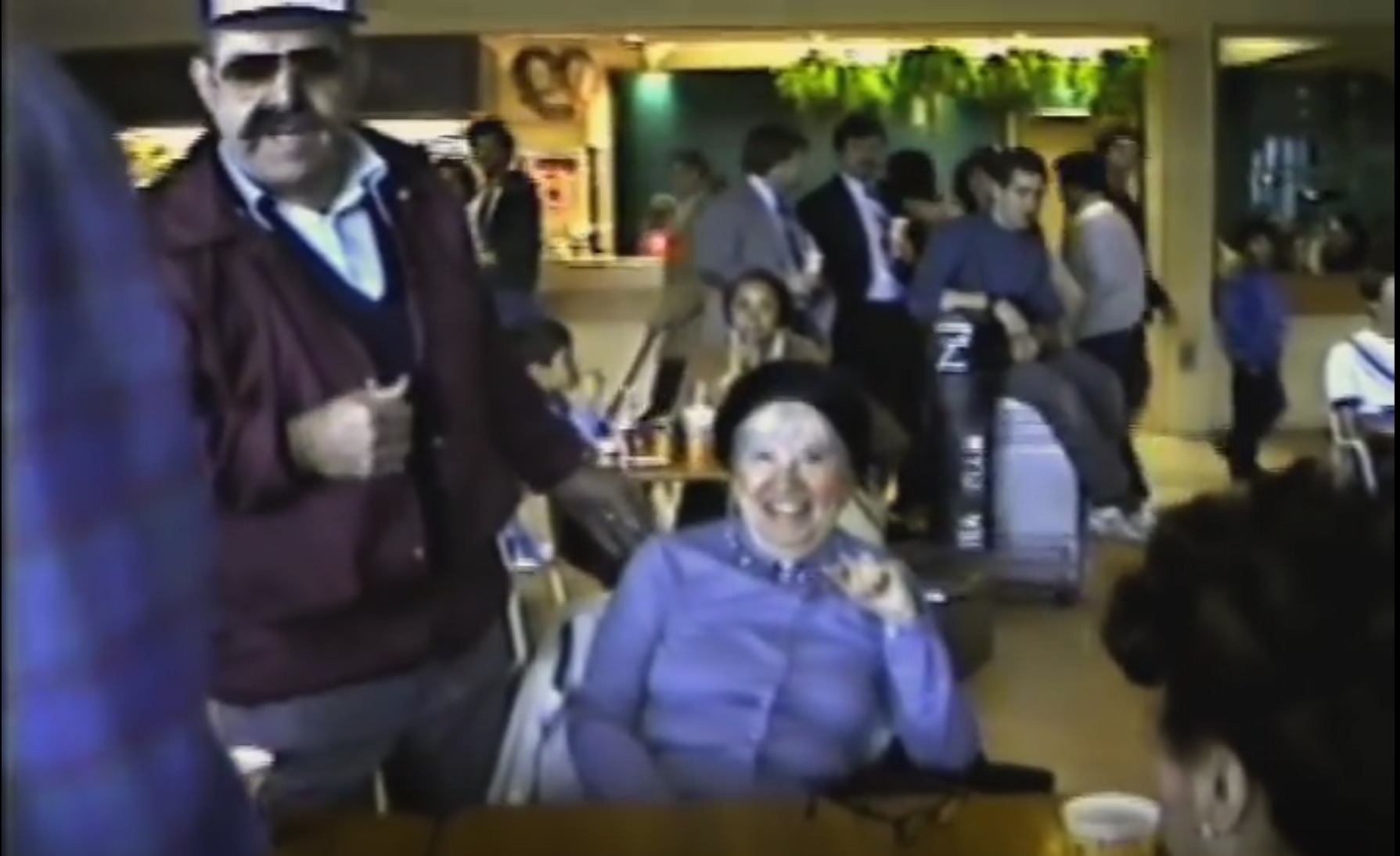 screenshot from the 1983 video documentary "Mall City." Pictures are senior citizens sitting at a table at a Long Island mall being interviewed by the filmmaker.
