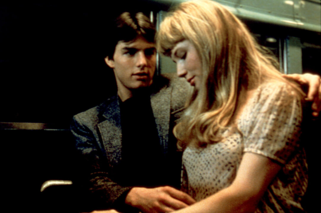 photo from the 1983 movie "Risky Business." It depicts Tom Cruise, left in the photo, and Rebecca De Mornay, seated to his left, sitting on a train. Cruise has his left arm around her shoulders, and his right hand on her lap.