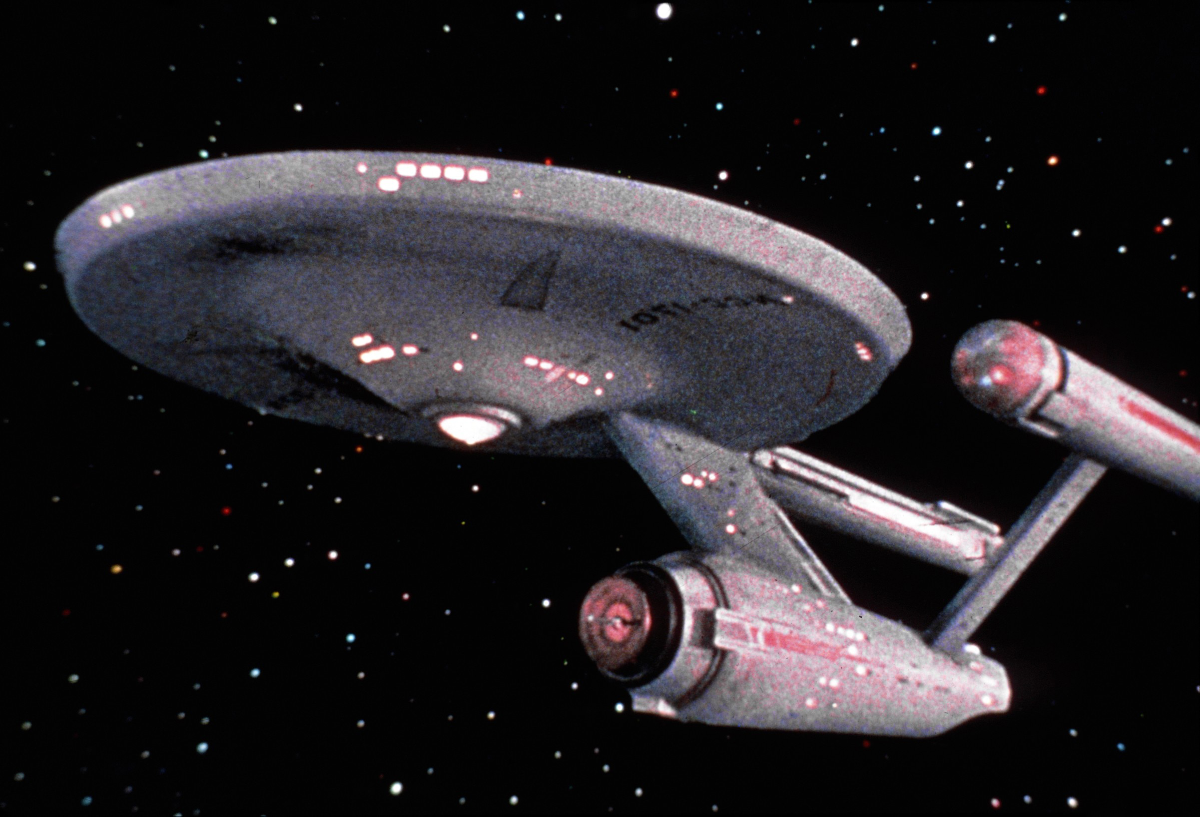 shot of the USS "Enterprise" starship as seen in the original 1966-69 series "Star Trek." The ship is set against the black backdrop of space, dotted with stars.