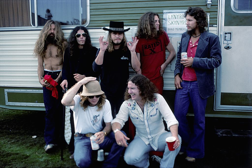 CALIFORNIA - OCTOBER 1976: Southern Rock band Lynyrd Skynyrd (L-R back row Artimus Pyle, Gary Rossington, Ronnie Van Zant, Allen Collins and Steve Gaines, front row Leon Wilkeson and Billy Powell) pose by their trailer backstage at an outdoor concert in October, 1976 in California