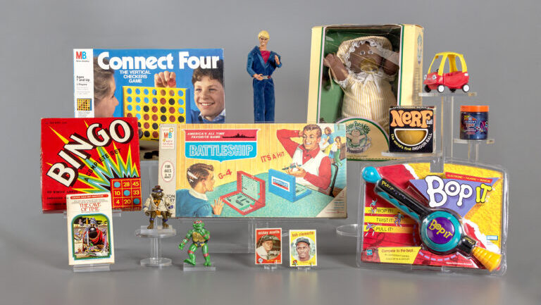 picture of the 12 finalists for 2023 induction into the National Toy Hall of Fame. Pictured are the board game Connect Four; the Ken doll; a Cabbage Patch Kid; a Little Tykes Cozy Coupe; a Nerf ball; slime; Bop It; Battleship game; a box containing a bingo game; a Choose Your Own Adventure book; decks of baseball cards; and two Teenage Mutant Ninja Turtle figures.