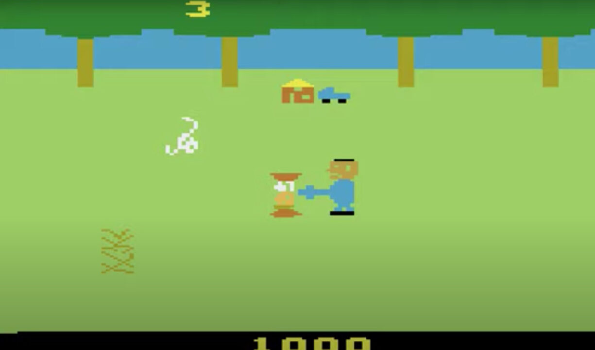 screenshot from the 1983 Atari 2600 video game "The Texas Chainsaw Massacre," based on the horror film. It shows an 8-bit version of the film's killer, Leatherface, on the right, with a pixelated item held out in front of him representing a chainsaw. Immediately in front of him is a victim he has just killed with the chainsaw, represented with 8-bit red areas for the blood.