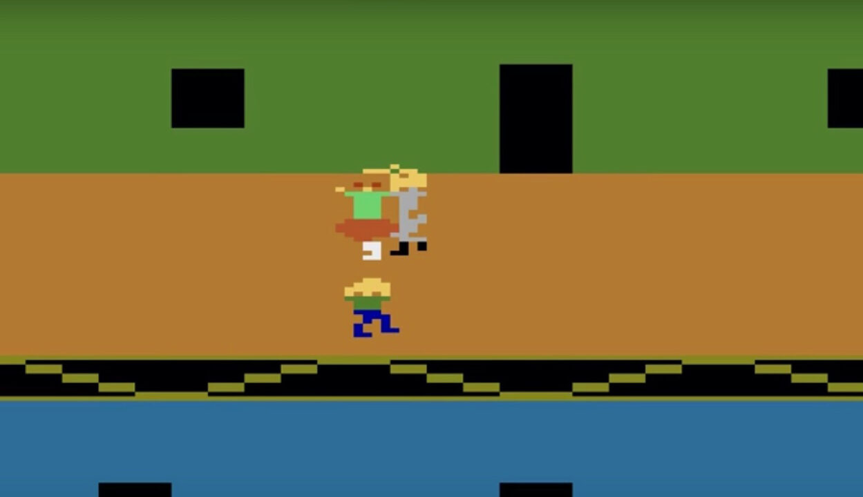 screenshot from the 1983 Atari 2600 video game "Halloween," based on the horror movie. It shows an 8-bit version of the movie's killer having just cut off a babysitter's head. Red digitized areas depict the blood coming out. Right next to them is an 8-bit shape meant to be the child who was in the babysitter's care.