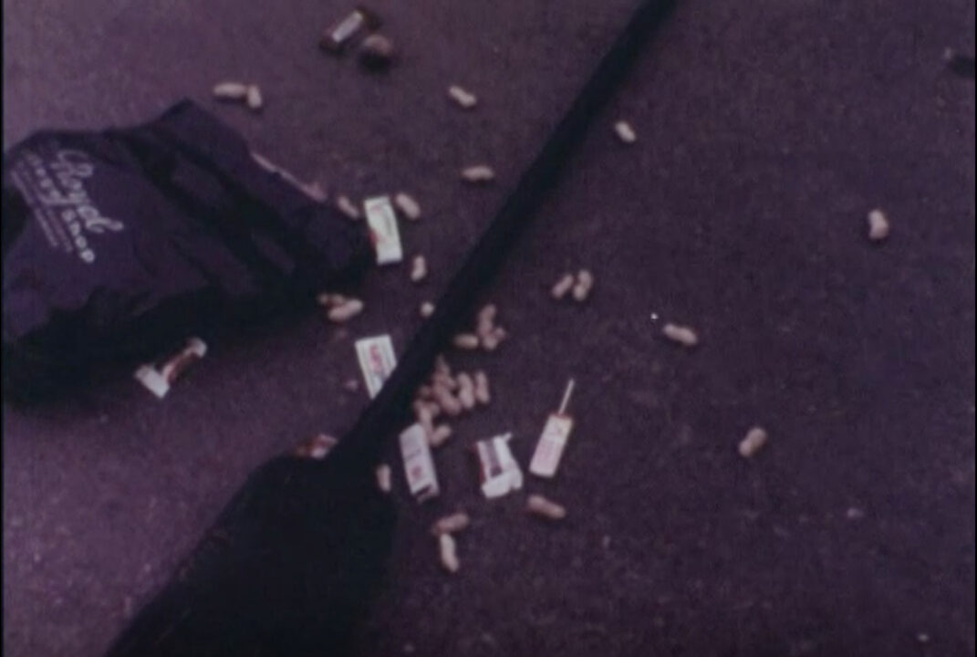 image from the 1977 short educational film "Halloween Safety." It is an image of spilled Halloween candy on a street after the girl holding the bag tripped over her unsafe costume.