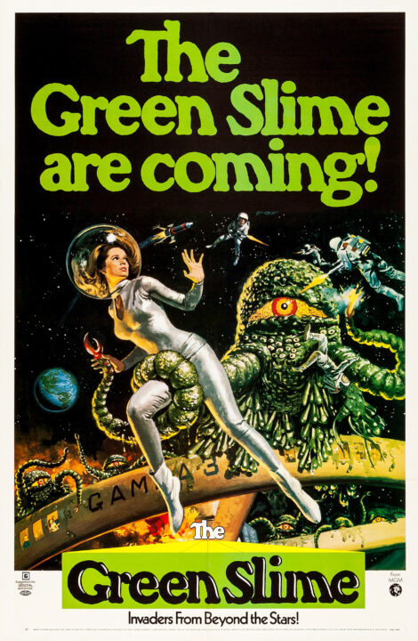 the movie poster for the 1968 movie "The Green Slime." In large green lettering at the top reads: "The Green Slime Are Coming!" Below that is an illustration of the outside of a round space station, with astronauts outside of it battling the title creatures against a starry background. In the foreground is a woman astronaut being grabbed by one of the monster's tentacles, wrapped around her right thigh as she looks back at it it horror. The creatures are large and green, with a single, large red eye in the center of their rounded heads.