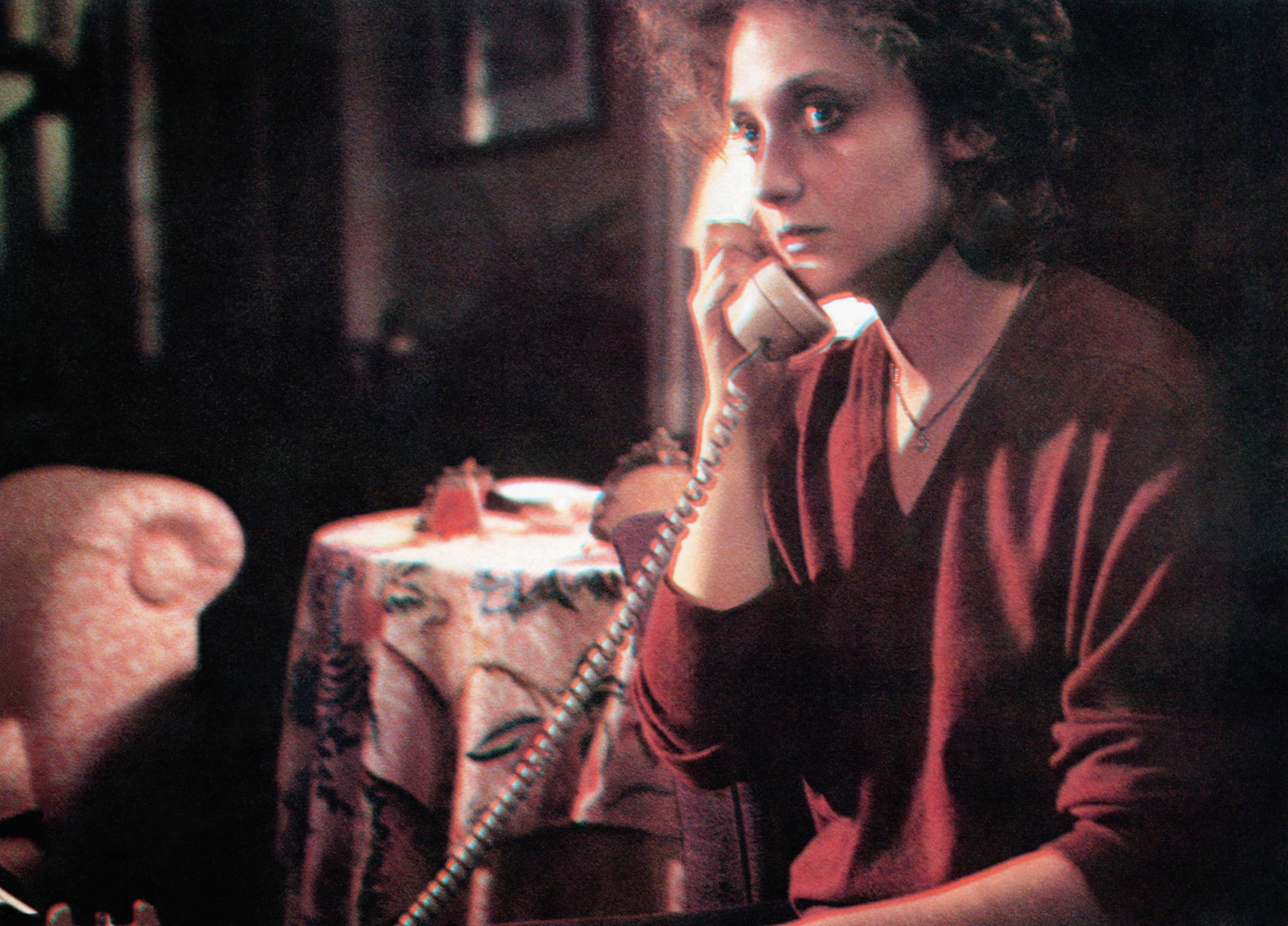 picture from the 1979 movie "When a Stranger Calls," depicting Carol Kane as a babysitter who has a look of fear on her face as she is listening to a killer speaking to her via telephone.