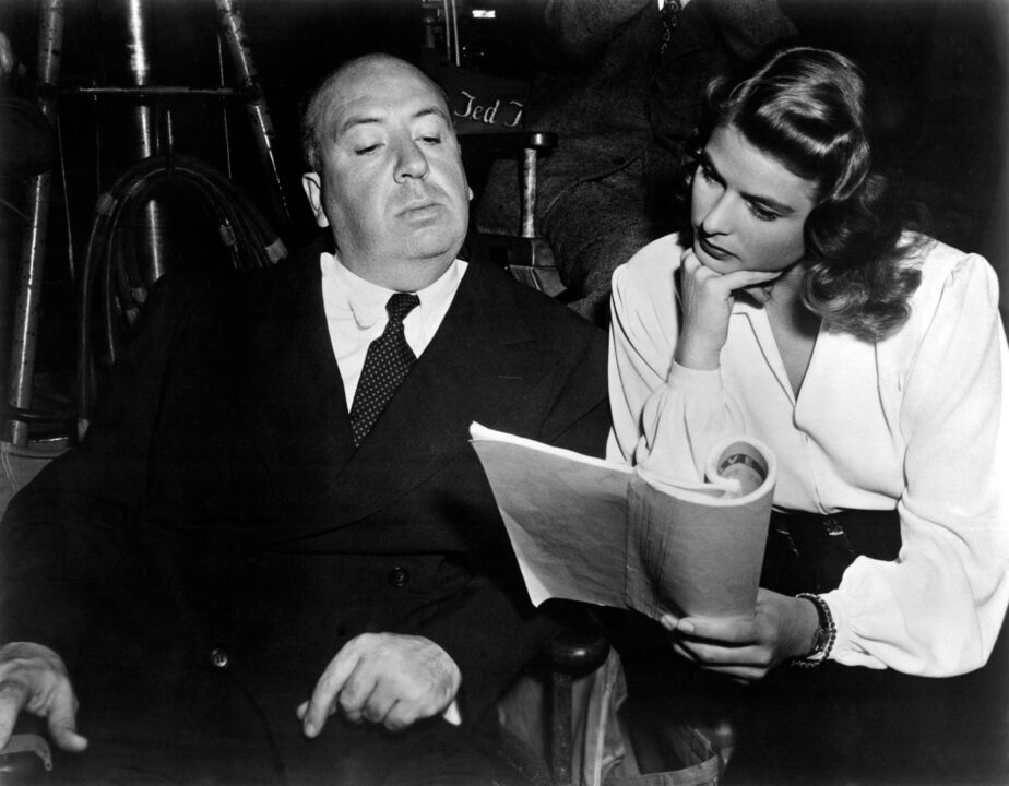 NOTORIOUS, Director Alfred Hitchcock reviewing script with Ingrid Bergman on set, 1946