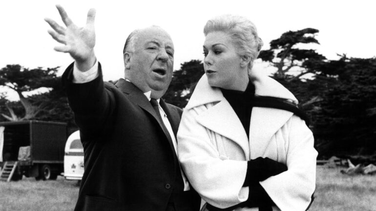 VERTIGO, Director Alfred Hitchcock hams it up on set with Kim Novak, 1958