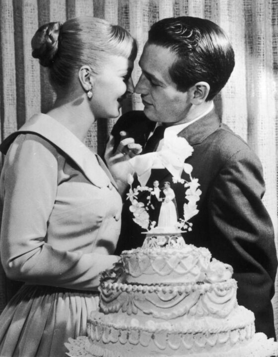 American actors and newlyweds Paul Newman and Joanne Woodward kiss behind a wedding cake during their wedding reception at the El Rancho hotel-casino, Las Vegas, Nevada, January 29, 1958