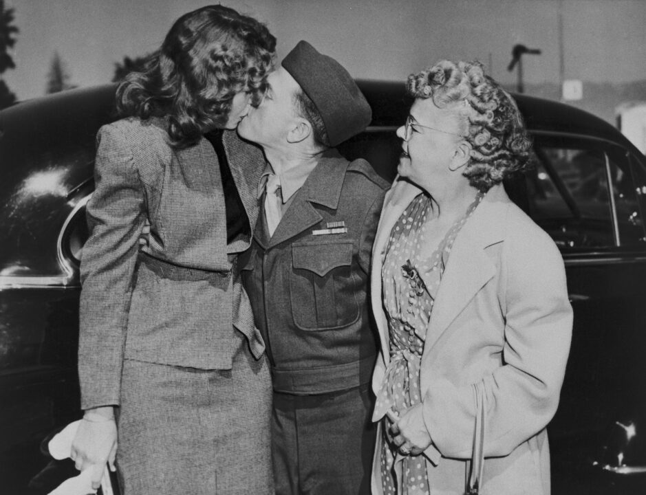 (Original Caption) Mickey Rooney Home From War, Greets Wife. Los Angeles, California: Mickey Rooney, home from the war, greets his wife, Betty Jane, with a big kiss today while his mother Mrs. Nell Pankey looks on. The Film star returned to Hollywood after several years in the service.