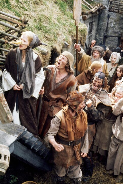 MONTY PYTHON AND THE HOLY GRAIL, Connie Booth (carrot nose), Eric Idle (second from left, yelling), Michael Palin (dirty, torn watchcap), John Cleese (dark leather cap), 1975