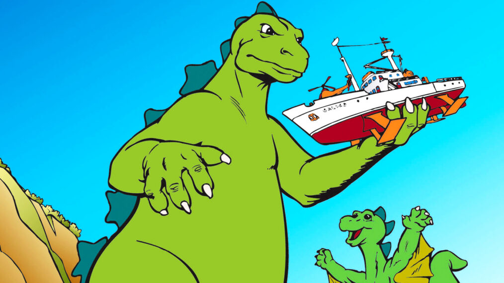 promotional image for the 1978 Godzilla cartoon series from Hanna-Barbera. Standing on a beach in front of a cliff, on the left of this illustration, is the animated figure of Godzilla; his body is light green, scales running down his back are darker green. He is facing the right of the image and his holding a ship in his left hand. Just below him and to his right, and much smaller, is the character Godzooky, who looks similar to Godzilla but has flaps beneath each arm that are lifting him aloft a few feet off the beach. Godzooky looks smiling and happy, while Godzilla has a serious look on his face.