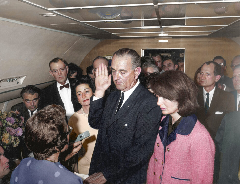 This colorized archival image shows the swearing-in ceremony of Lyndon B. Johnson (LBJ) as President aboard Air Force One with former first lady Jacqueline Kennedy standing next to him, Nov. 22, 1963, in Dallas. 