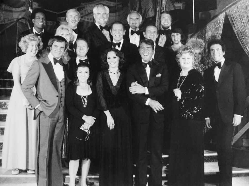 black-and-white 1975 group shot from "The Dean Martin Celebrity Roast." front from left: Rich Little, Nancy Walker, Valerie Harper, Dean Martin, Shelley Winters, David Groh, middle from left: Georgia Engel, Zsa Zsa Gabor, Red Buttons, Milton Berle, Jack Carter, Julie Kavner, Phyllis Diller, rear from left: Nipsey Russell, Jack Albertson, Foster Brooks, Harold Gould, Chad Everett
