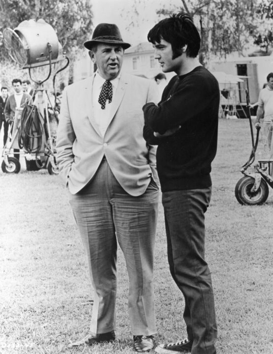 LOS ANGELES - CIRCA 1963: Rock and roll singer and actor Elvis Presley confers with Colonel Tom Parker on the set of one of his films