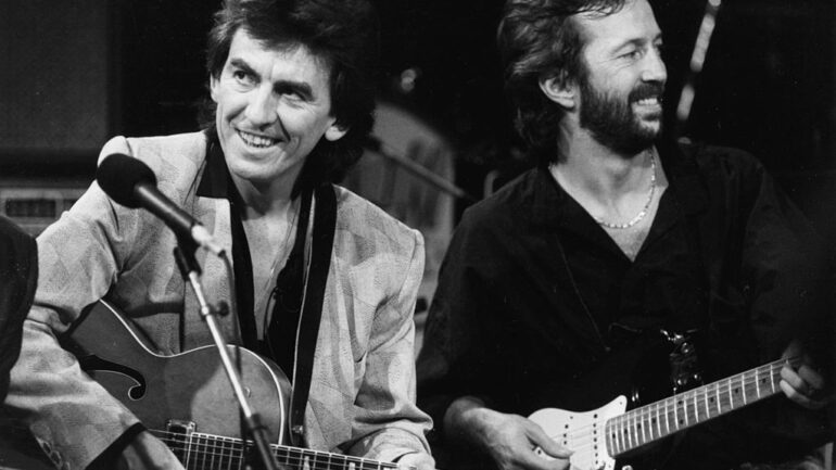 Musicians George Harrison (left) and Eric Clapton performing on stage together as part of an all-star band for music legend Carl Perkins, October 23rd 1985