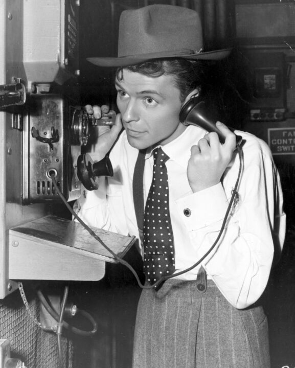 circa 1940: A young Frank Sinatra making a telephone call on the set of the film 'Step Lively'