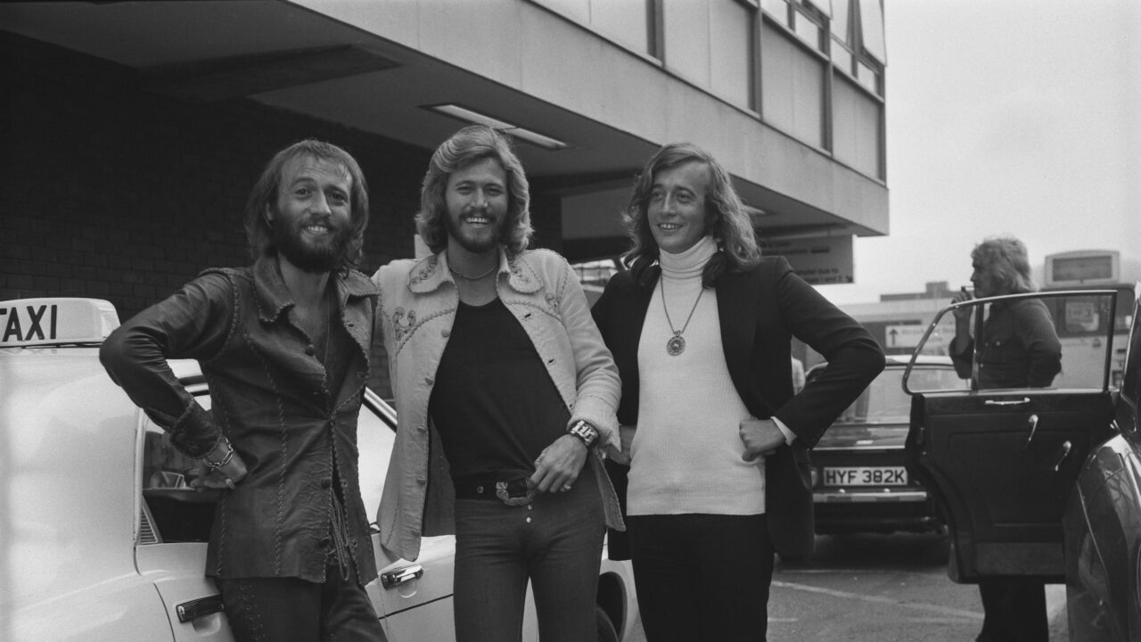 Pop group the Bee Gees arrive at Heathrow Airport in London, UK, July 1973. From left to right, Maurice, Barry and Robin Gibb. 