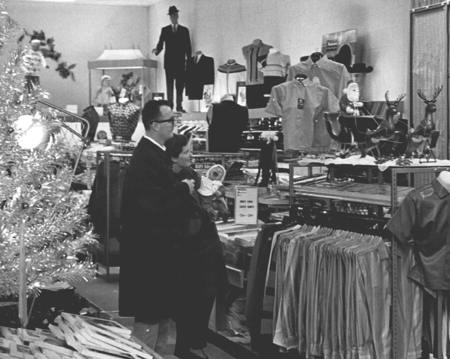 black and white 1964 photo from the Denver Post featuring a man named Kris Kingle, his wife named Nellie and their infant son named Kris Kringle Jr. doing some Christmas shopping.