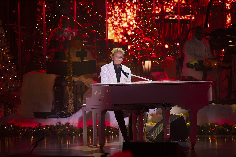BARRY MANILOW'S A VERY BARRY CHRISTMAS, Barry Manilow playing piano with holiday decor in background