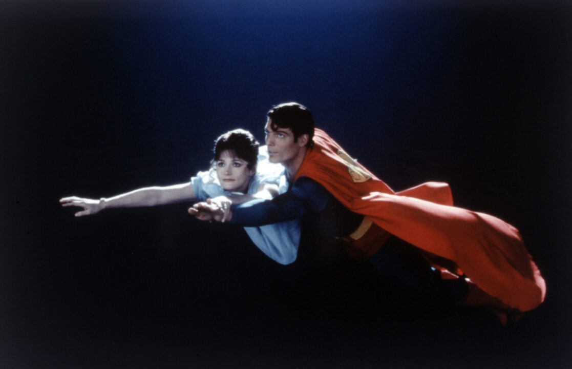 image from the 1978 movie "Superman." It is a scene where Superman (Christopher Reeve) is taking Lois Lane (Margot Kidder) flying at night. Superman is on the right of the photo, gently holding Lois as they fly and guiding her as he stretches out her right arm and smiles in amazement.