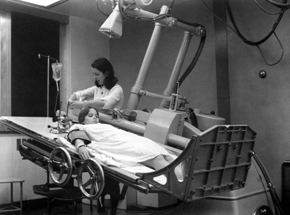 black and white still from the 1973 movie "The Exorcist," of the scene in which Regan (Linda Blair) is lying on a hospital bed and about to be given a spinal tap.