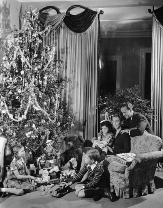 1950s: Family gathered around Christmas tree with gifts