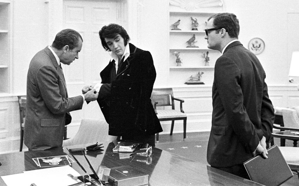 American politician US President Richard Nixon (1913 – 1994) takes a closer look at the cuff links of Rock and Roll musician Elvis Presley (1935 - 1977) during a meeting at the White House, Washington DC, December 21, 1970. At right is Nixon's aide, Egil Krogh Jr (1939 - 2020).