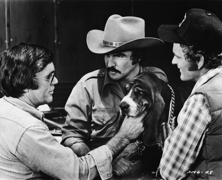 American director Hal Needham lines up a shot with actors Burt Reynolds and Jerry Reed and Happy on the set of the movie 'Smokey and the Bandit,' 1977.
