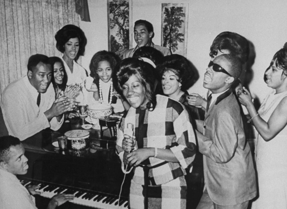 Motown founder and pres. Berry Gordy playing the piano as group incl. Smokey Robinson (rear) and Stevie Wonder (2R) join in singing together at Motown Studios. 