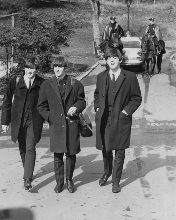 Left to right: John Lennon (1940 - 1980), Ringo Starr and Paul McCartney, of English pop group The Beatles, in Central Park, New York, 8th February 1964. Following them is a mounted police escort. 